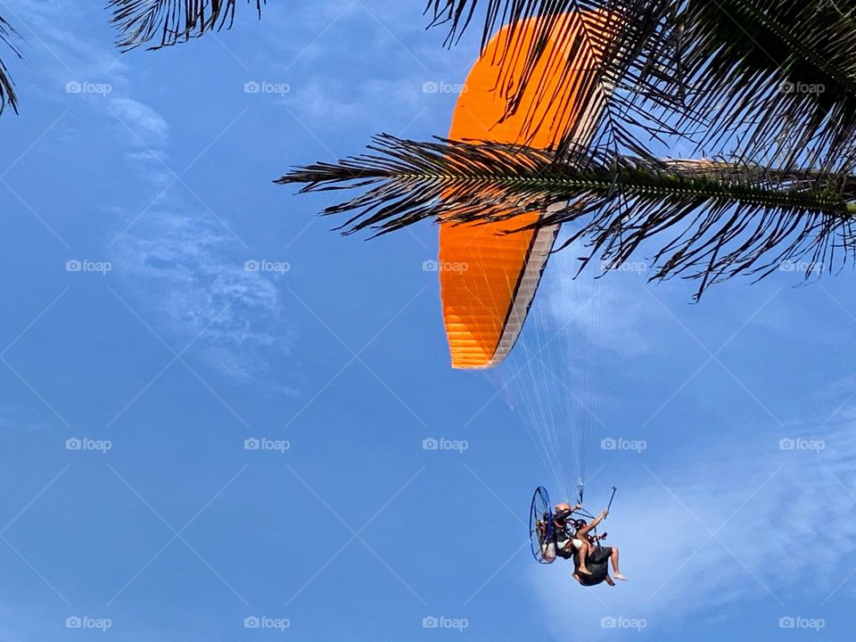 Orange paraglider in the blue sky
