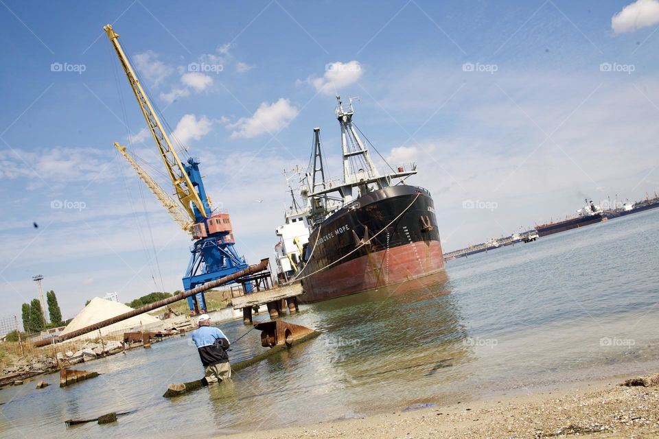 Большой корабль в порту и одинокий рыбак 