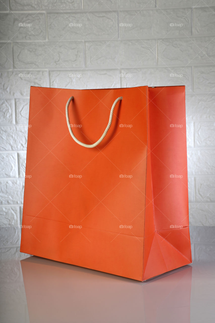 Orange shopping bag with white brick wall in the background