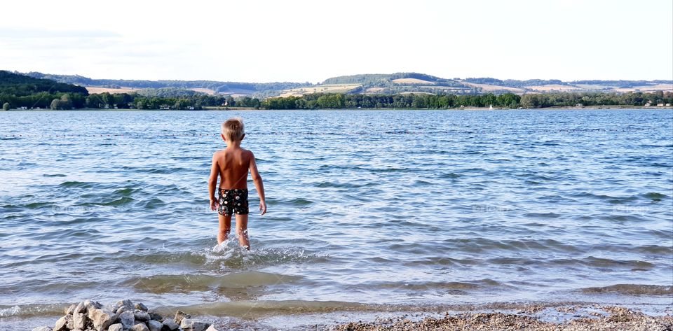 Boy about to take a swim in lake
