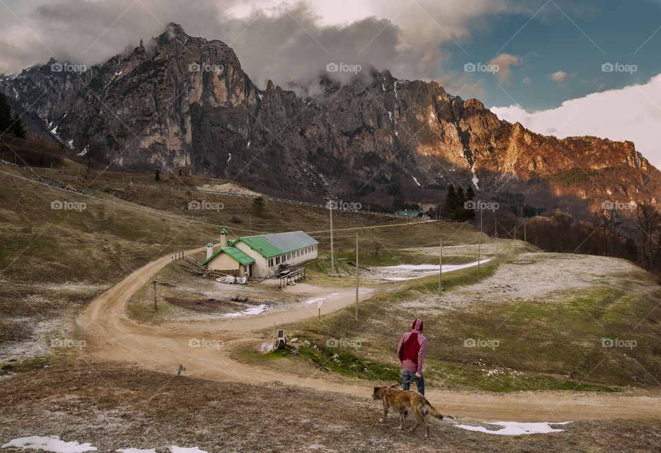 man walk with dog against mountains