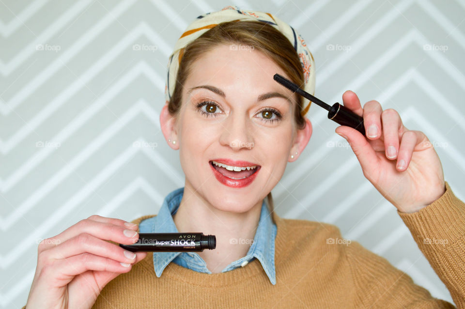 Woman applying AVON Super Shock mascara to eyelashes