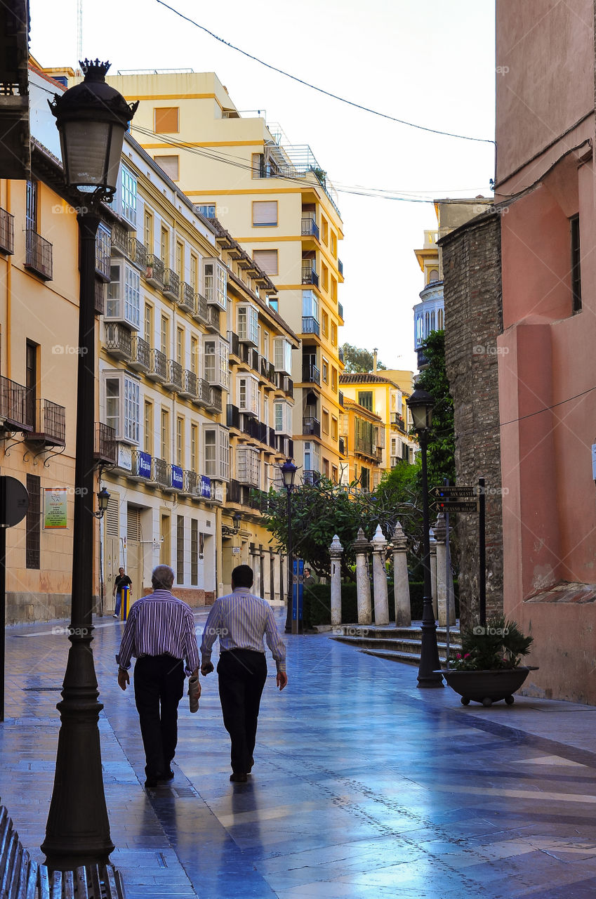 Two men walking on empty street of Malaga in the morning 