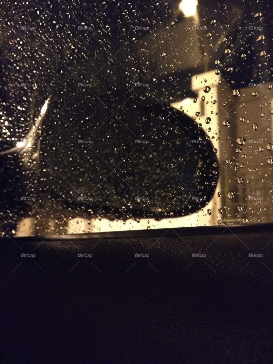 Noche lluviosa, espejo de auto con gotas