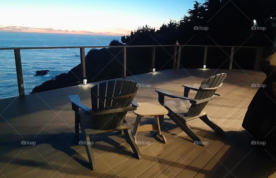 Empty Adirondack chairs on deck at sunset