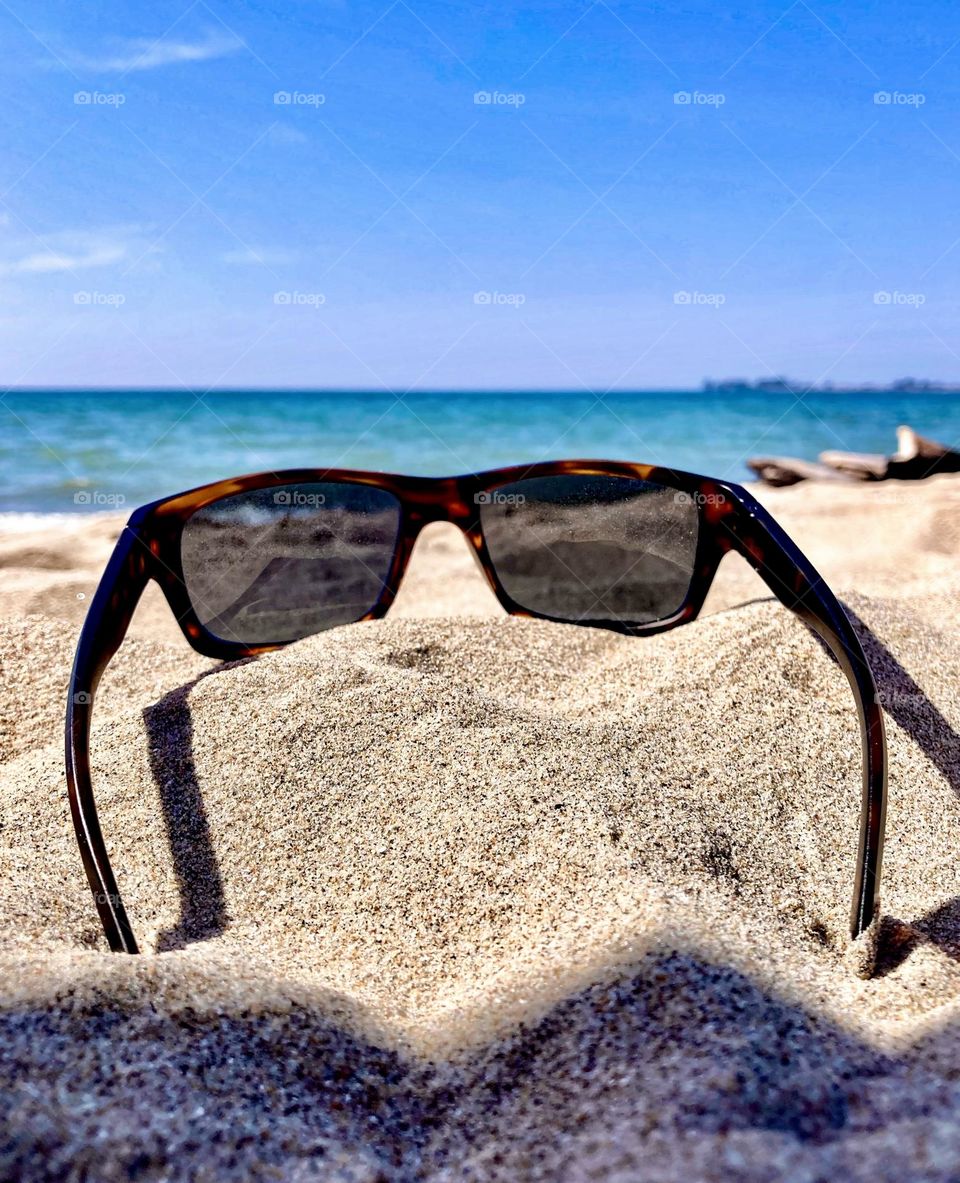 Sunglasses resting on the beach in the summer sun.