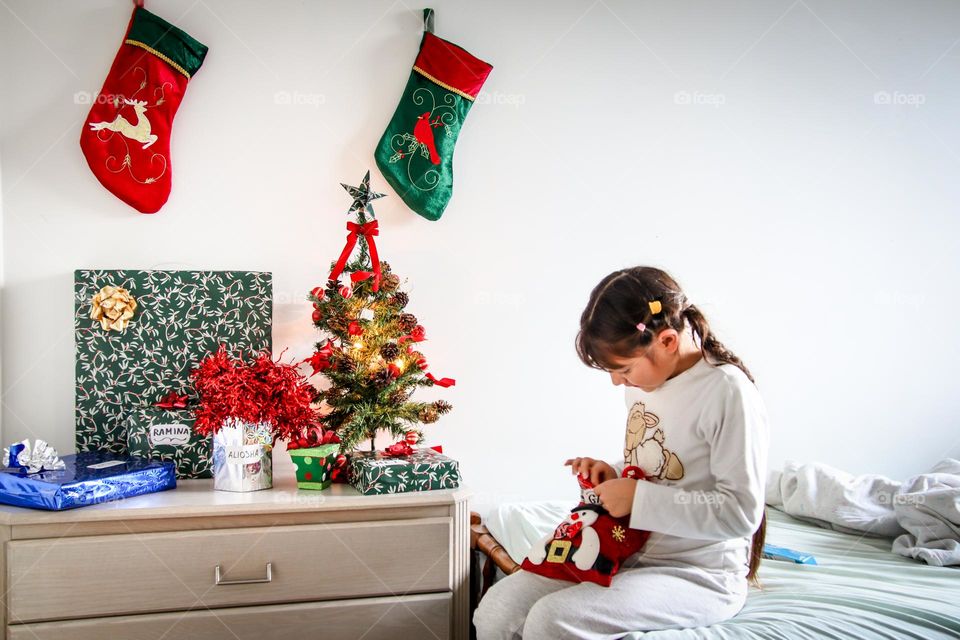 Cute child is opening her Christmas presents