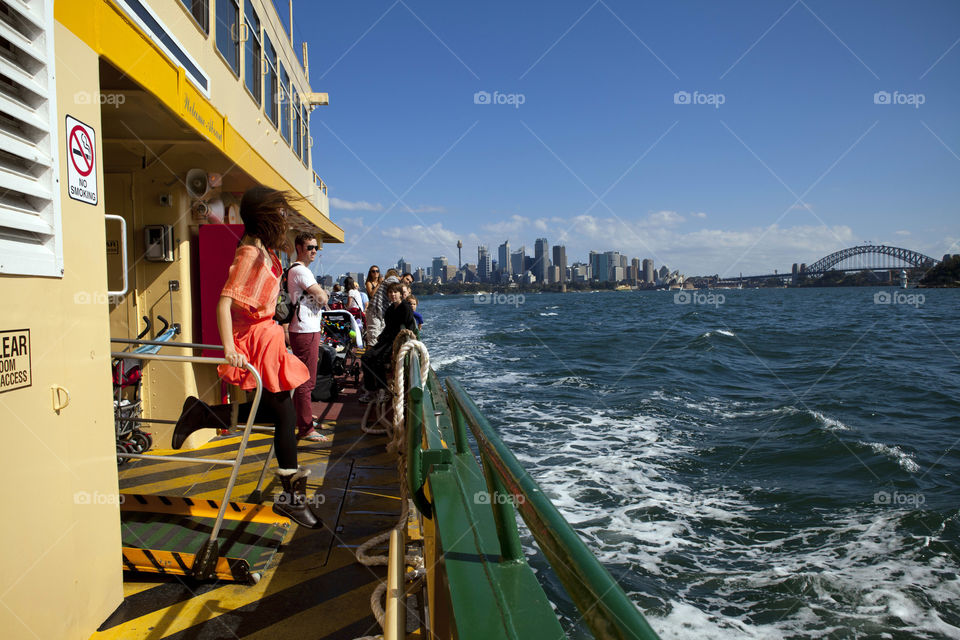 Lady leaping with excitement on a ferry ride to Taronga with the city and Harbor Bridge view