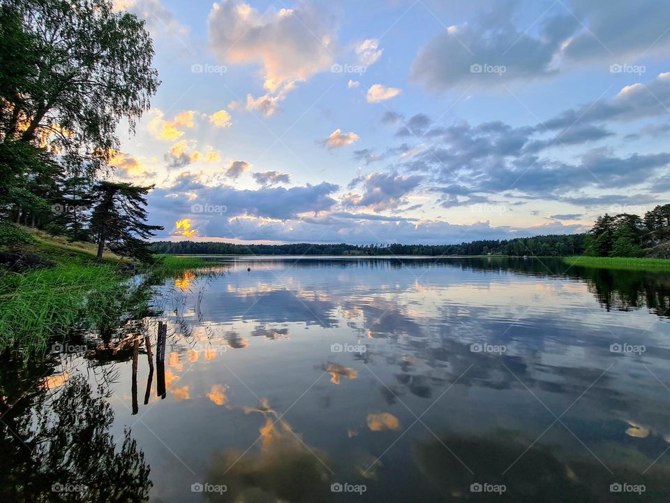 Amazing sunset scene over the Baltic Sea archipelago with clouds reflection in the still mirror smooth water surface