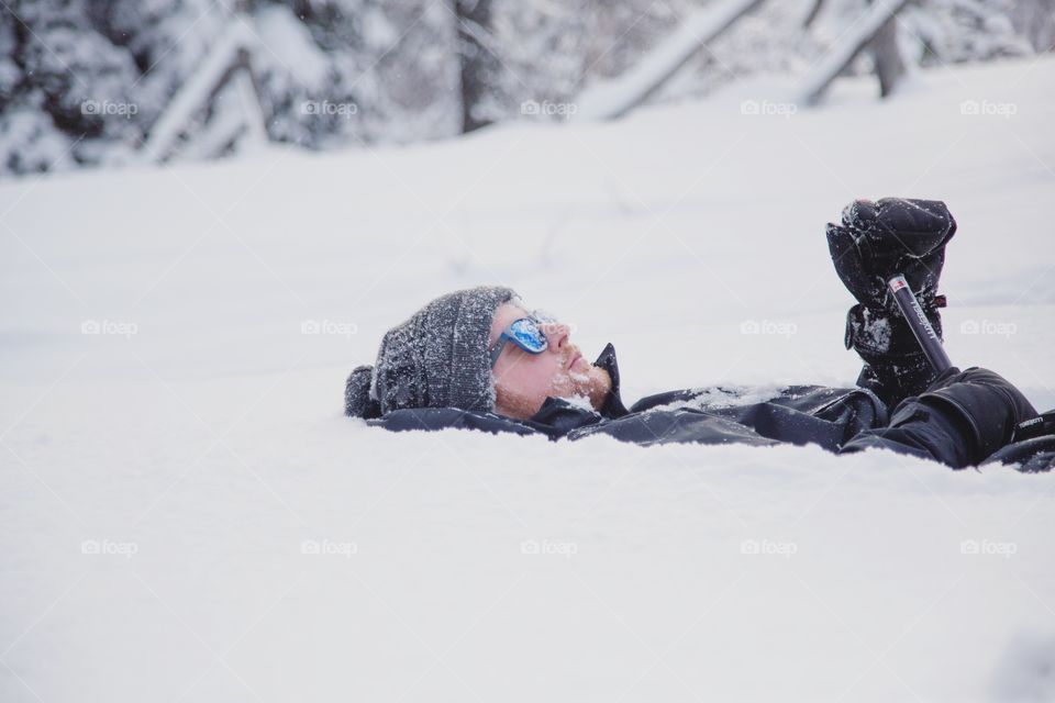 A young man lying in pure white snow