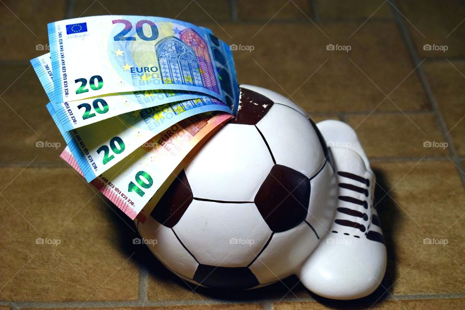 Money in a piggy bank. Euro in a piggy bank - a soccer ball