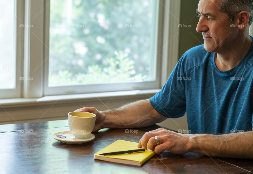 Man having a cup of tea and writing in his Journal 