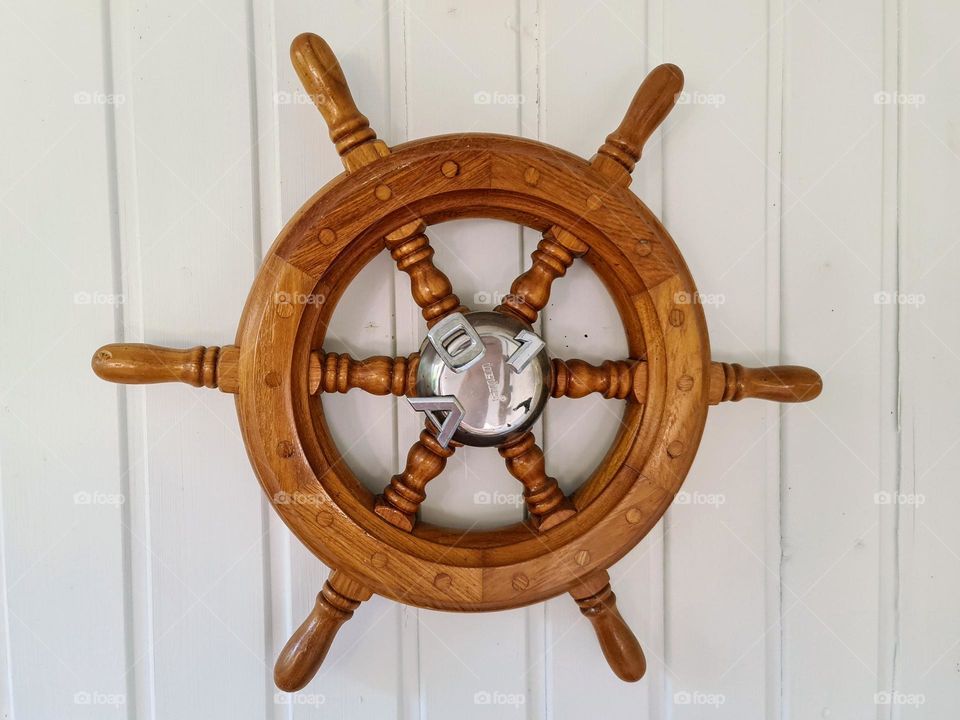 Decorative wooden steering wheel with silver middle on the white wall 