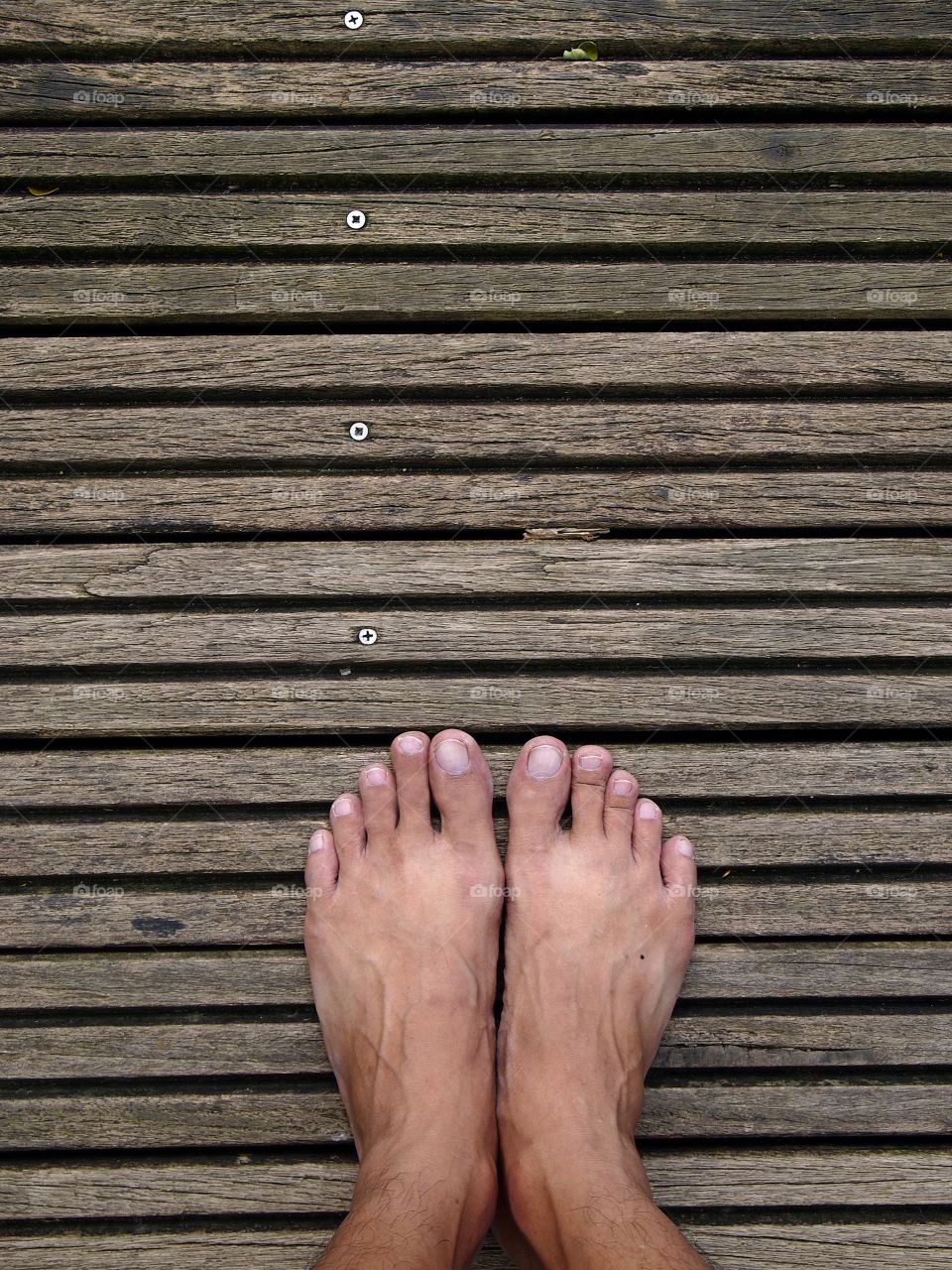 pair of feet standing on wooden floor