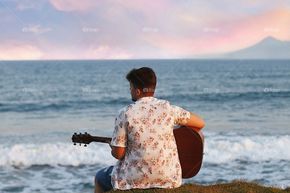 the boy with his guitar on the beach