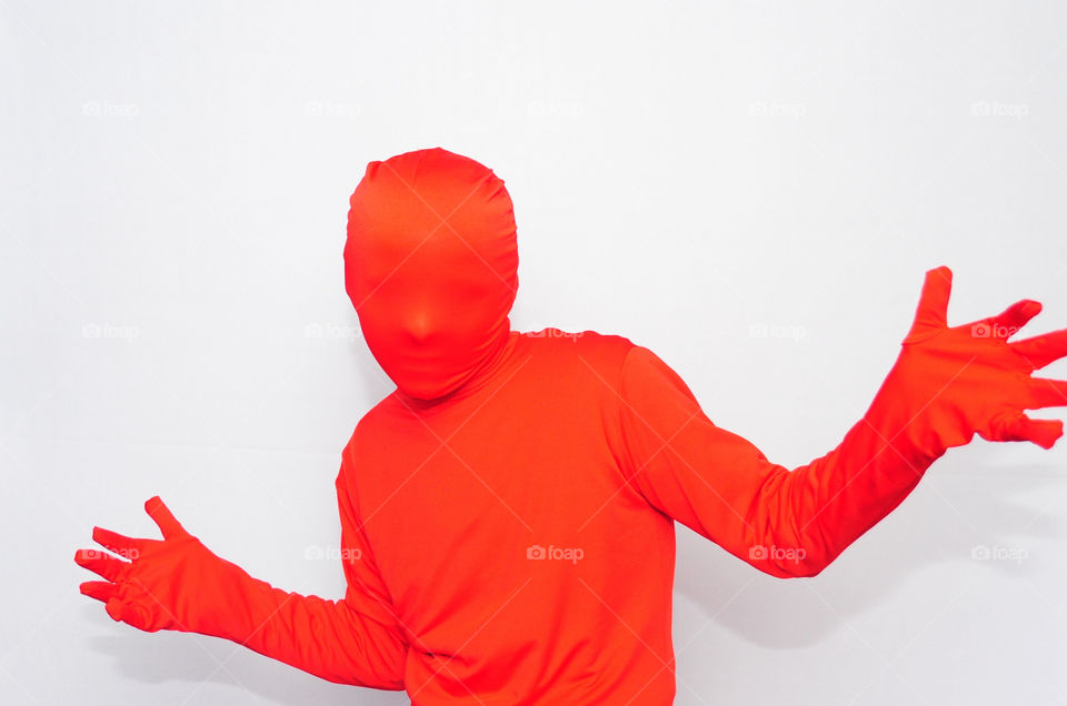 Young man in a red morph suit, in front of a high key white background. Color mission red, pop of red