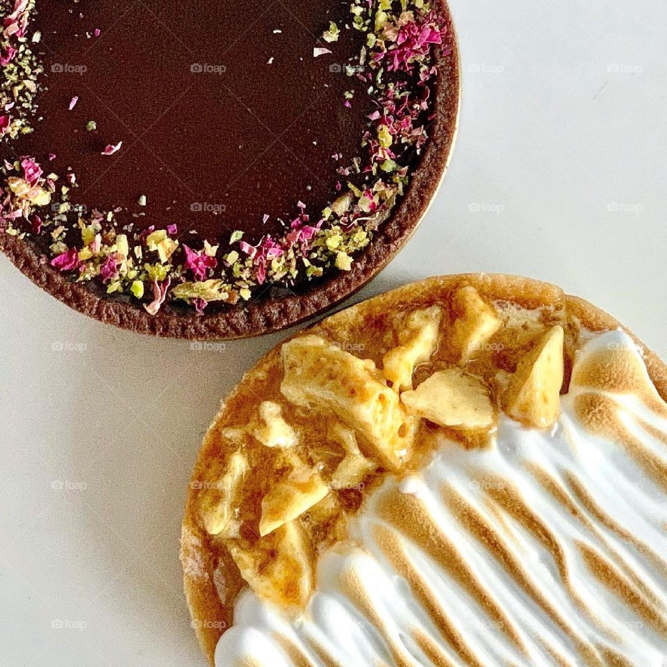Perfect duo tart in chocolate pistachio rose tart and lemon strawberry meringue tart flatlay 