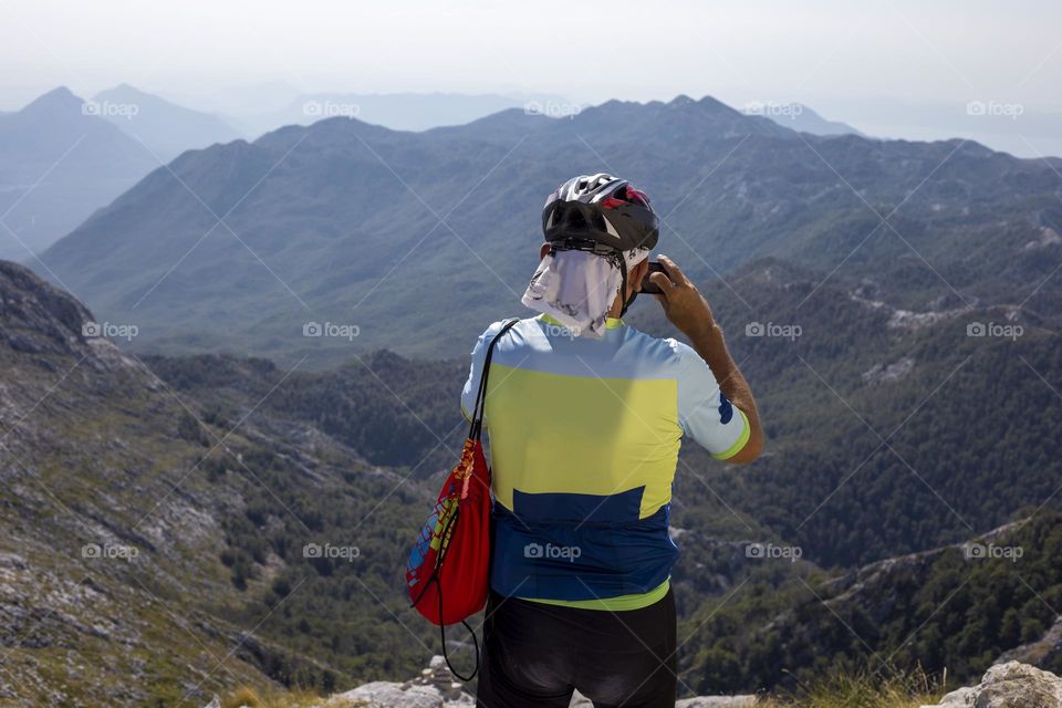 Man in the mountains talking pictures with his phone 