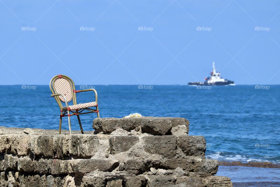 A chair on old stones wall by the sea