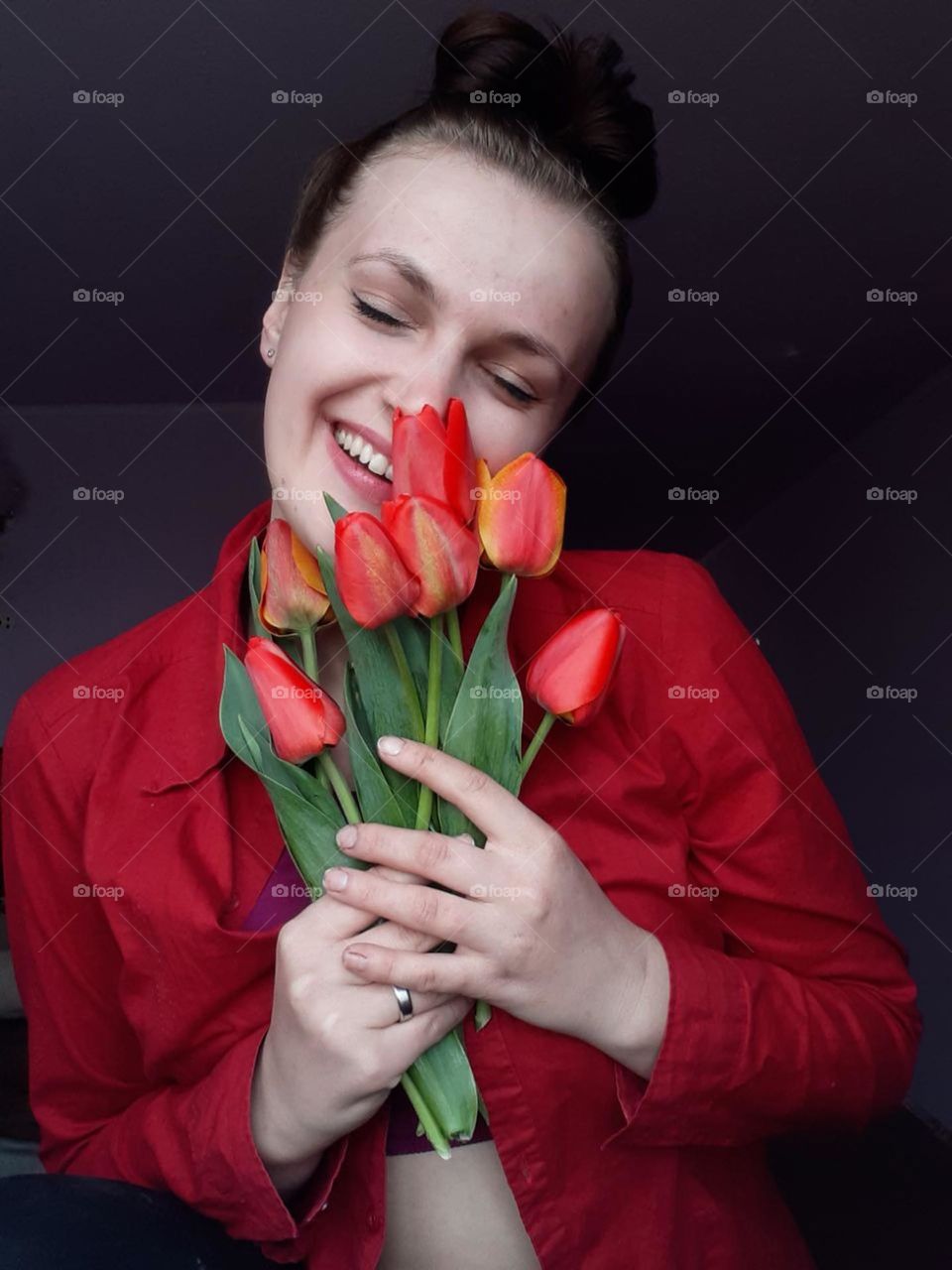 beautiful portrait of a young girl with a bouquet of garden red tulips with green leaves