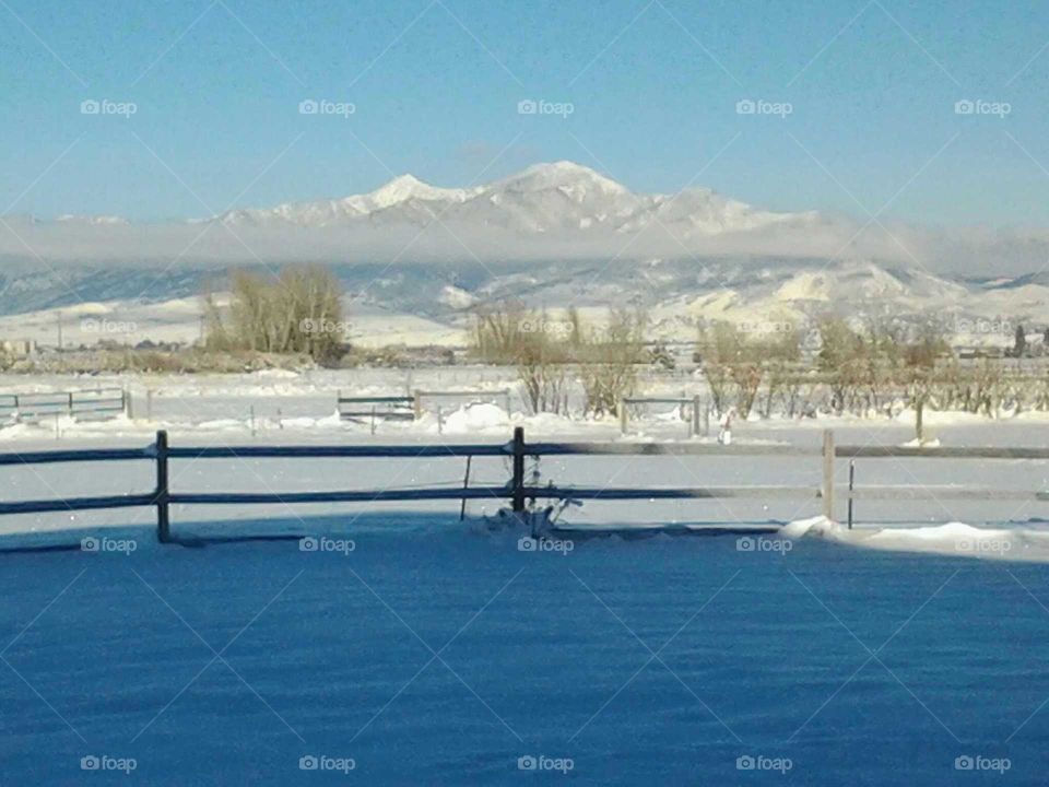 snow covered mountains with a fence