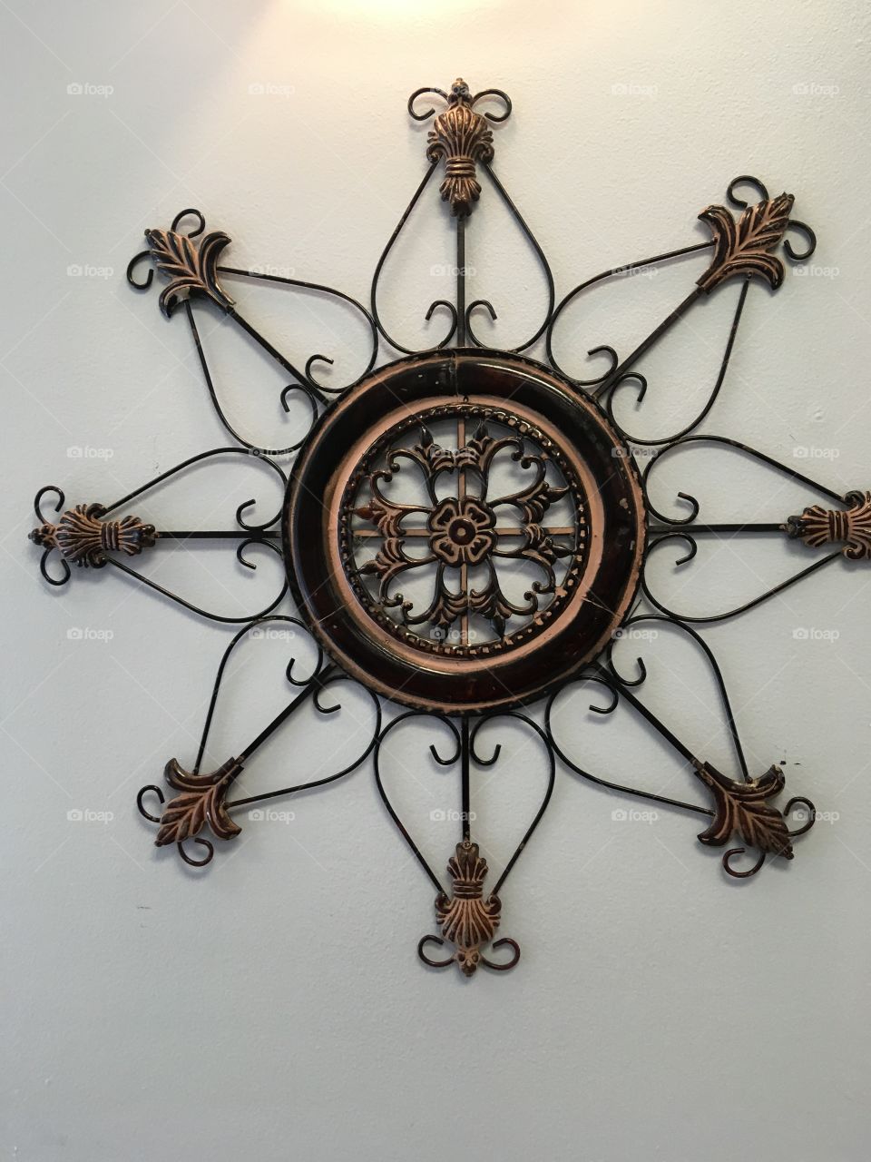 Flower shaped wall art made out of iron. Crosses hearts and bows make up the design.