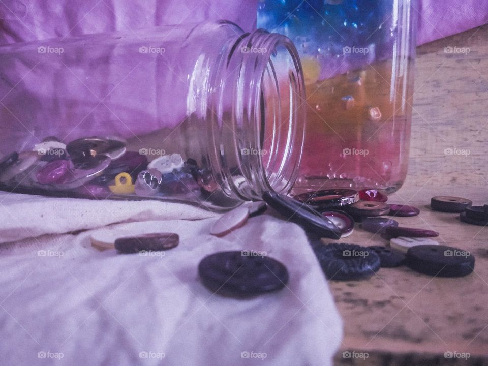This is a creative and a colourful idea.There is a bottle with a full of colourful marbles and there is a bottle with buttons.Some of bottons are laying on the surface and however this is very creative and colourful idea..❇️