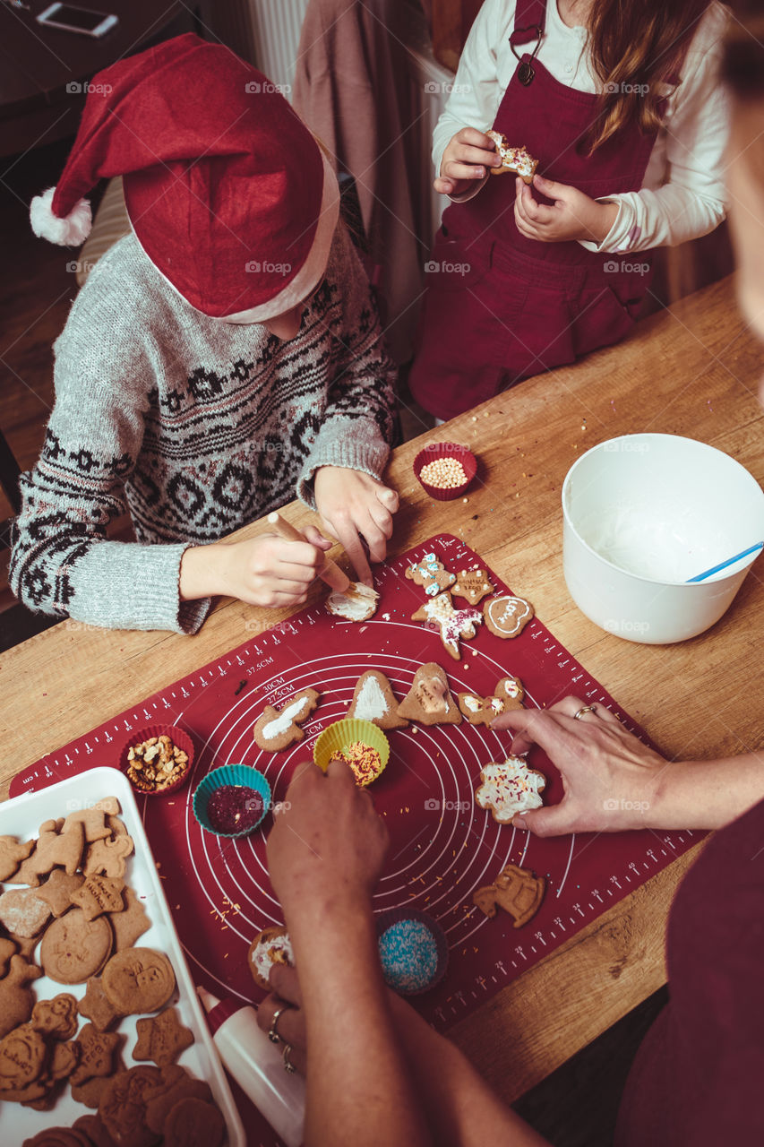 Baking Christmas cookies. Christmas gingerbread cookies in many shapes decorated with colorful frosting, sprinkle, icing, chocolate coating, toppers, put on table. Baking traditional cookies. Family celebrating Christmas. Baking at home