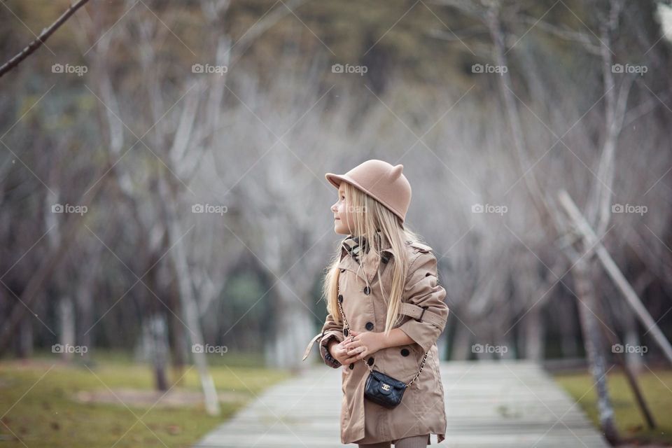 Stylish little Caucasian girl walking in park 