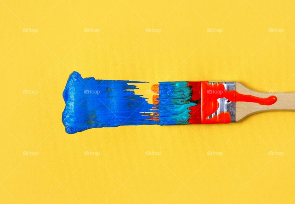 Colorful painted paintbrush on yellow background
