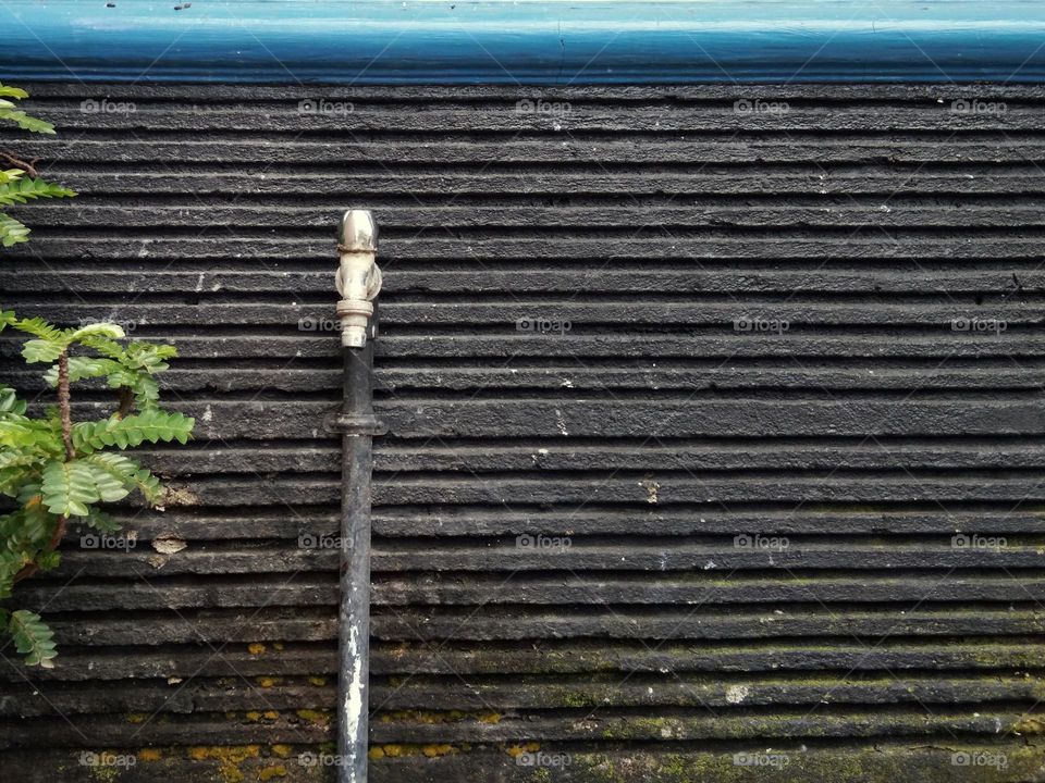 water faucet on the black wall in striped pattern