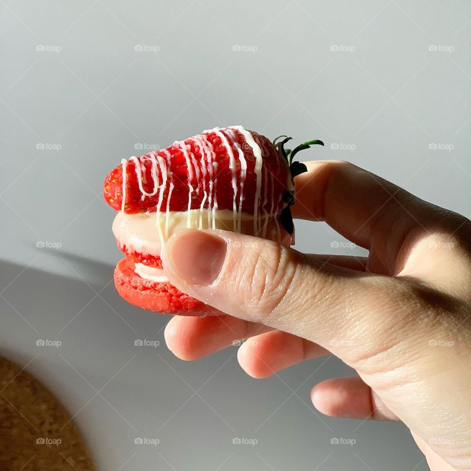 Holding on to a strawberry cheesecake fat macaron under the sunlight 
