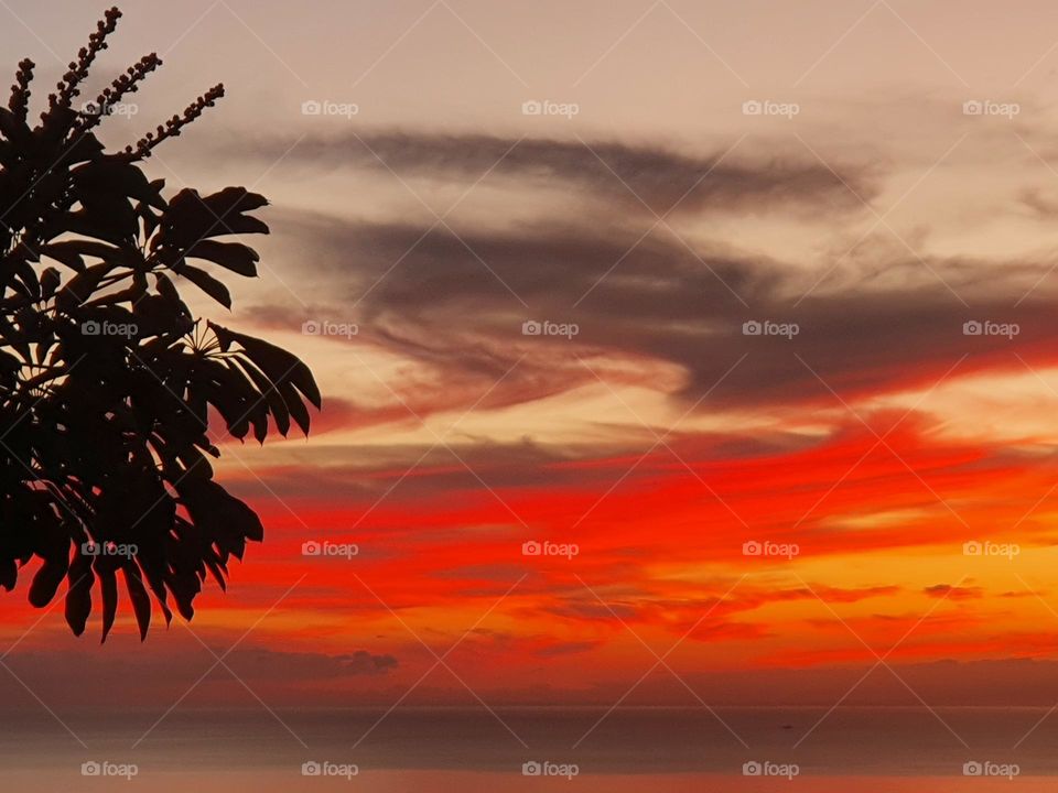 colorful sunset at the ocean, fiery red, playful clouds