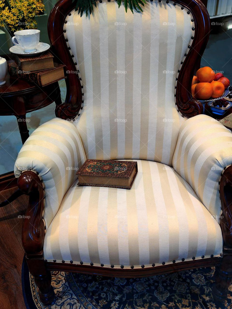 Armchair with a book. Wooden tea table with porcelain tea set and vase with yellow flowers