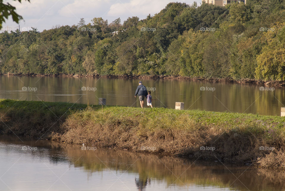 Grandfather and grandson take a walk along the Raritan river in the famous and historic Boyd park in New Brunswick, New Jersey.