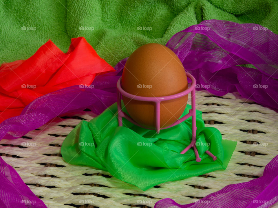 Brown eggs of light color prepare for the holiday Easter against the background from a white rope and dark branches of a tree with bright multi-colored ribbons.