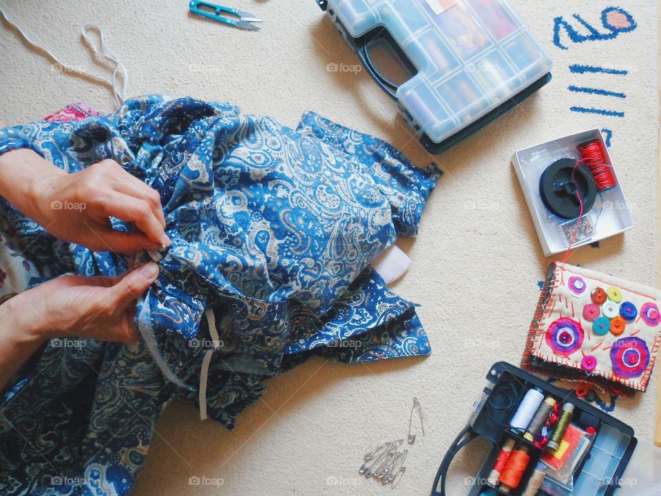 woman sews clothes in hand