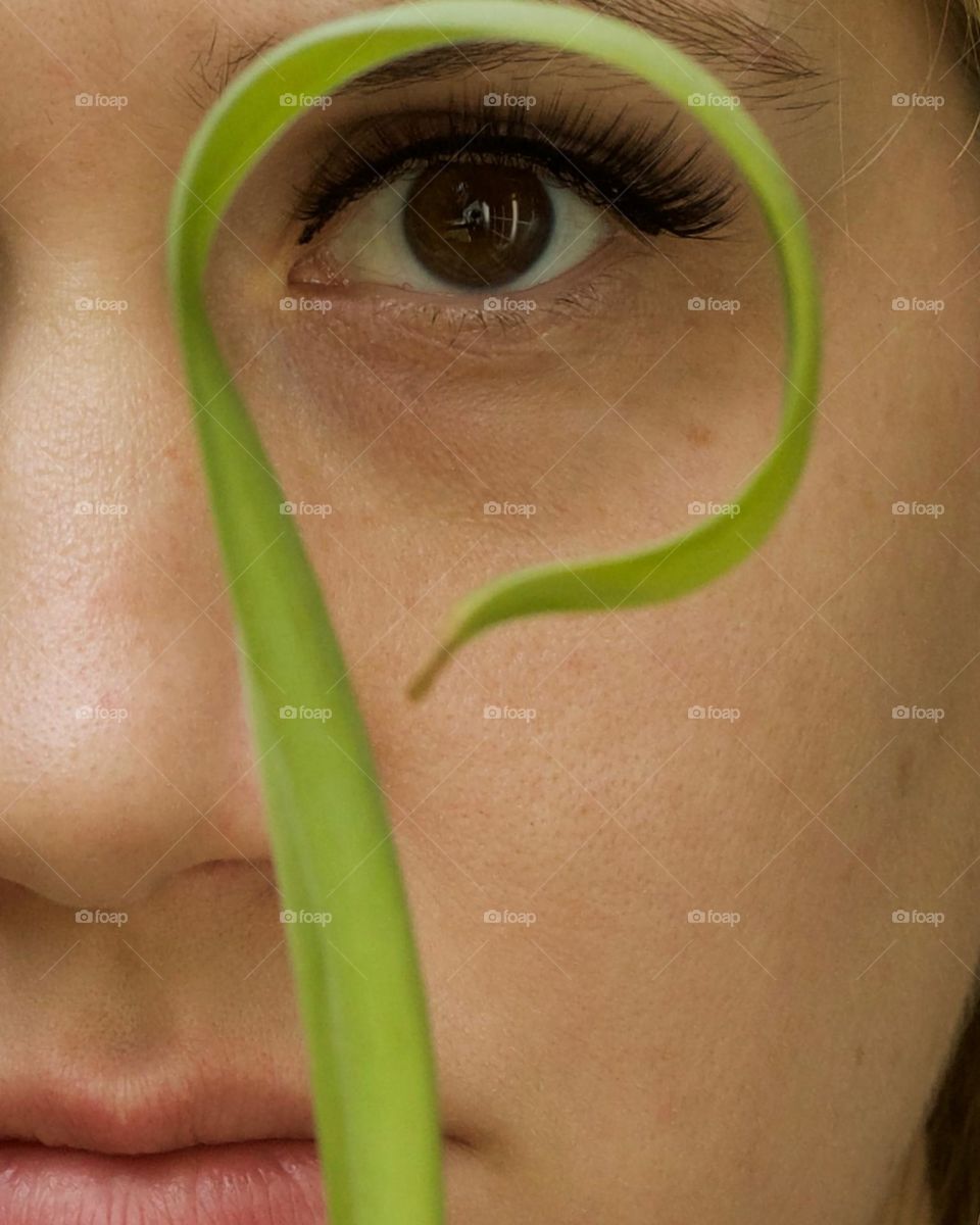 Woman looking through a curled Lily leaf