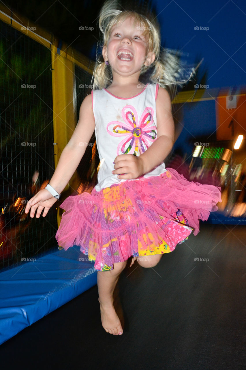 young girl jumping trampoline at theme park in Majorca island.