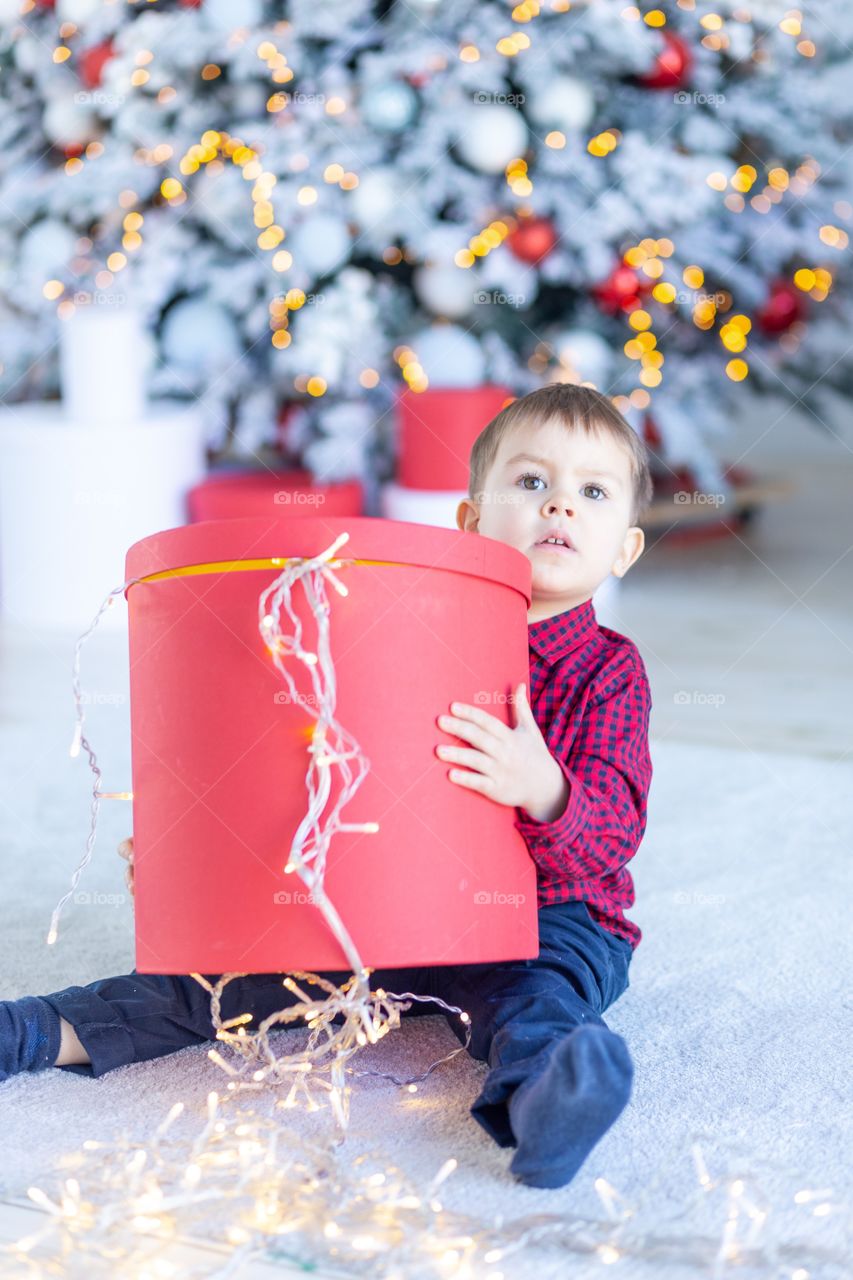 boy and gift box next to christmas tree