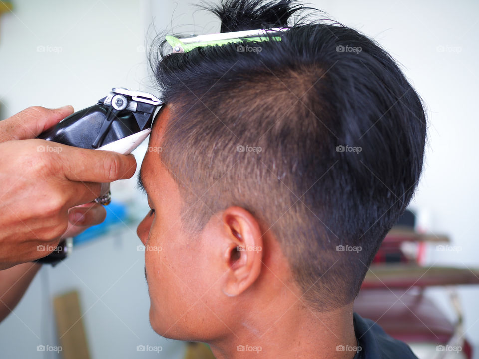 man getting haircut at barber shop. Hairdresser cutting hair of customer at salon.