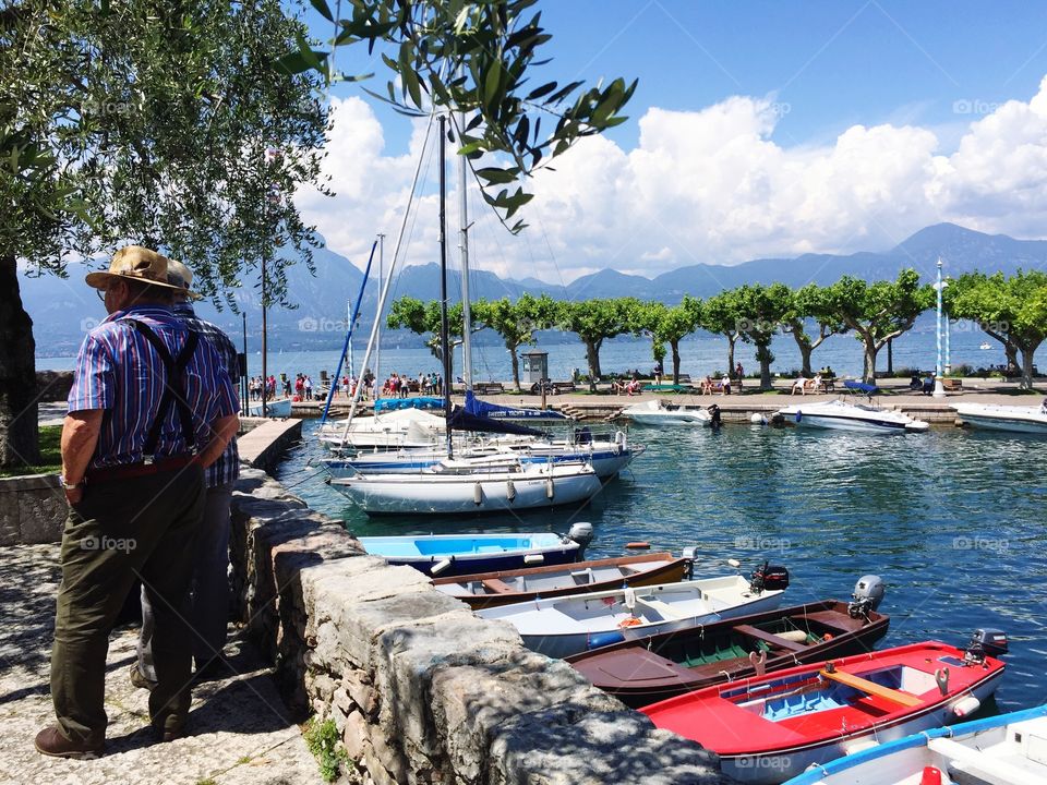 Group of men and small Port of Torri del Benaco at Lake Garda, Italy