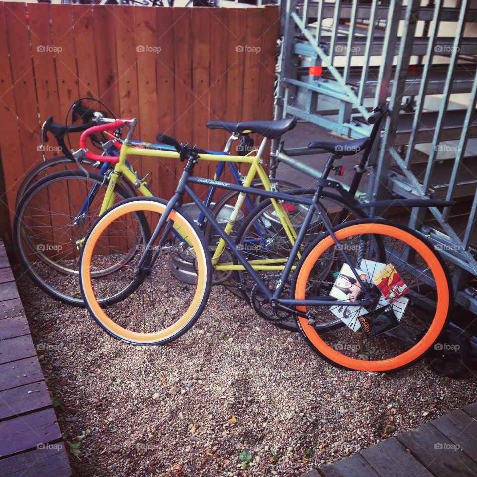 Grey brakeless fixie bike with orange wheels together with yellow and blue roadbikes after the bike race in Moscow, Russia