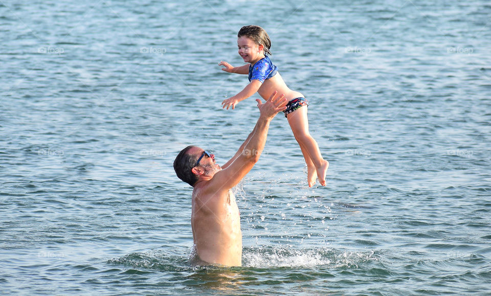 Father playing at the beach with his little daughter