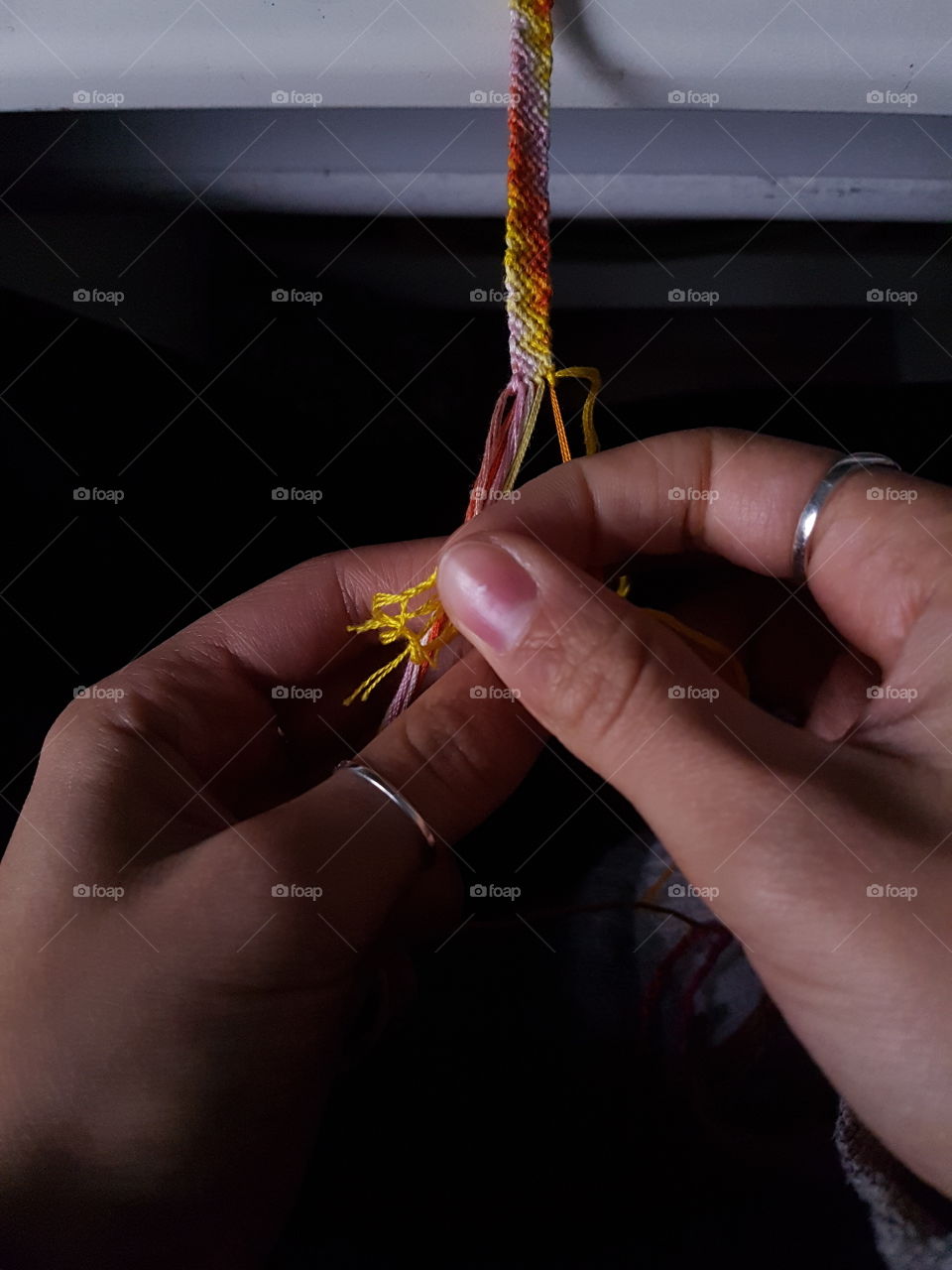 Working hands making a weaved bracelet