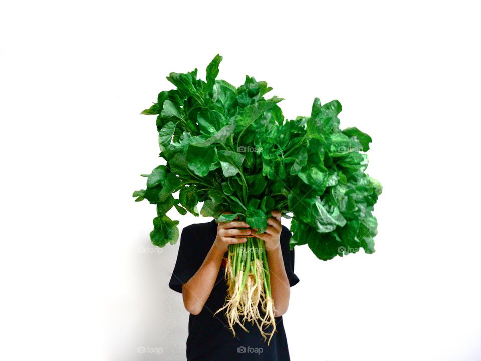 A boy holding a bunch of fresh spinach