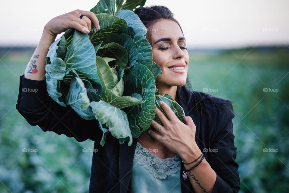 beautiful girl, in black clothes, stands in a spring field and holds a cabbage, emotions, the smell of spring