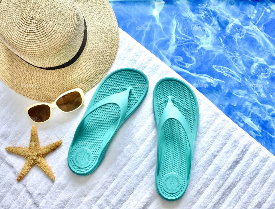 Flat lay still life of a summer scene with flip flops sunglasses starfish and a hat
