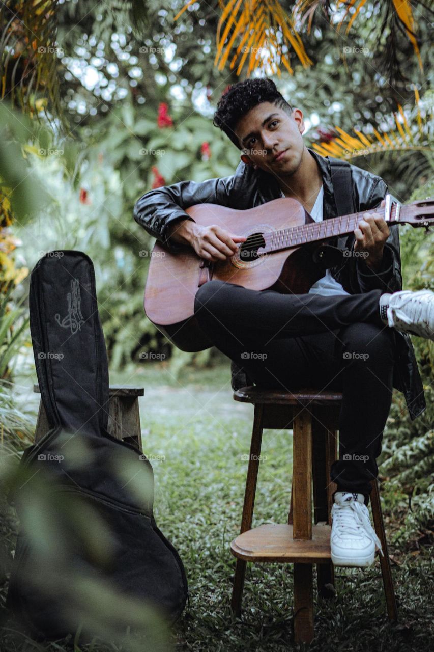 Boy playing guitar in the middle of nature