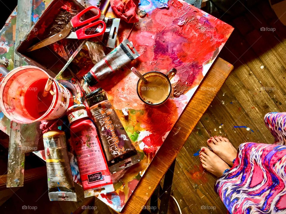 Feet view on painting table full of colors. 